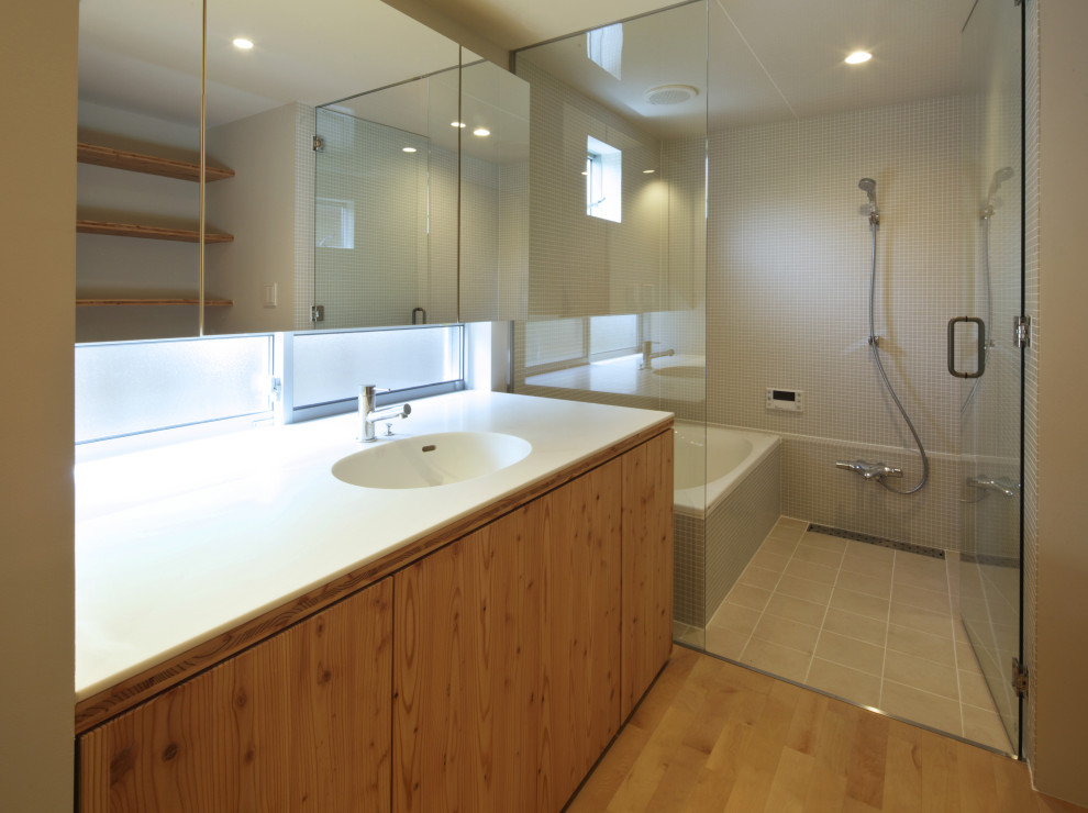 Idée de décoration pour une salle de bain de taille moyenne avec un carrelage beige, mosaïque, un mur blanc, parquet clair, un lavabo intégré et un plan de toilette blanc.