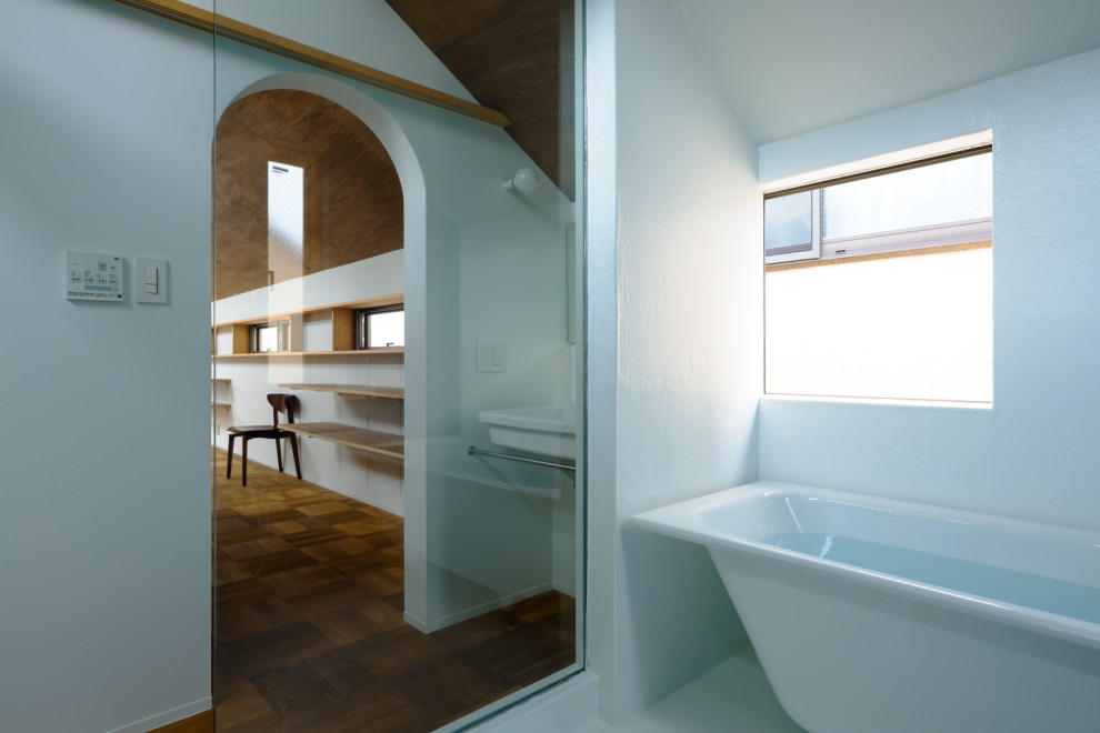 Small modern ensuite wet room bathroom in Tokyo with open cabinets, a freestanding bath, a two-piece toilet, white tiles, white walls, a wall-mounted sink, white floors, a sliding door, a single sink, a floating vanity unit and a timber clad ceiling.