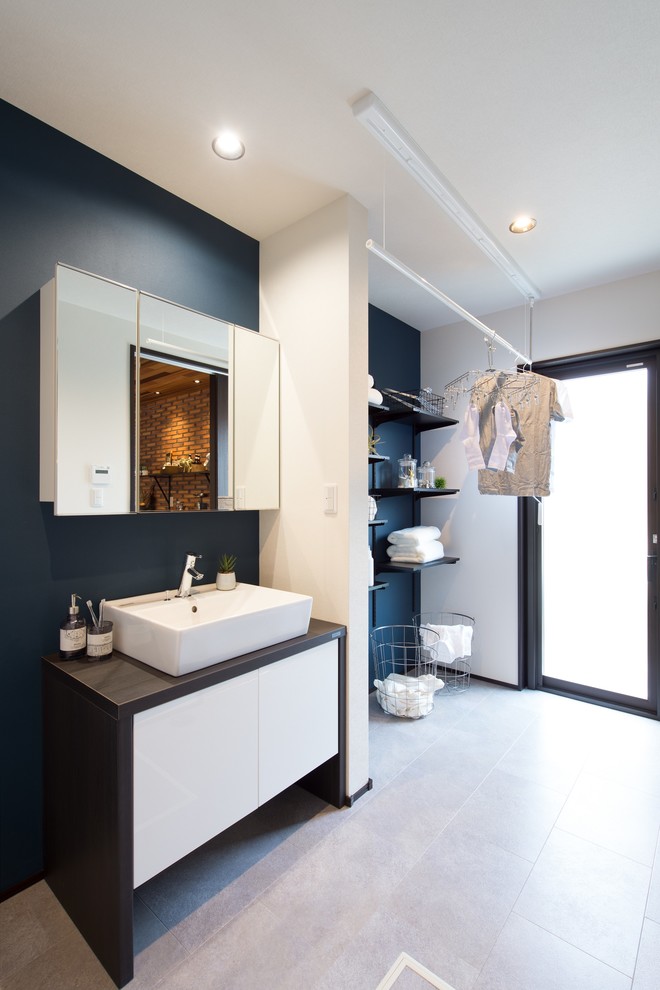 Modernes Badezimmer mit flächenbündigen Schrankfronten, weißen Schränken, schwarzer Wandfarbe, Aufsatzwaschbecken, grauem Boden und brauner Waschtischplatte in Sonstige