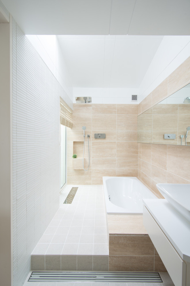 Minimalistisk inredning av ett vit vitt en-suite badrum, med vita skåp, en jacuzzi, en dubbeldusch, en toalettstol med hel cisternkåpa, beige kakel, marmorkakel, beige väggar, klinkergolv i keramik, ett nedsänkt handfat, grått golv och med dusch som är öppen