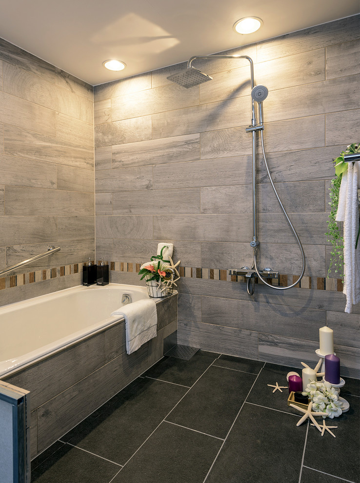 Cette image montre une salle de bain principale design de taille moyenne avec une baignoire posée, une douche double, un mur gris, un sol noir, un carrelage gris, des carreaux de porcelaine et un sol en carrelage de porcelaine.