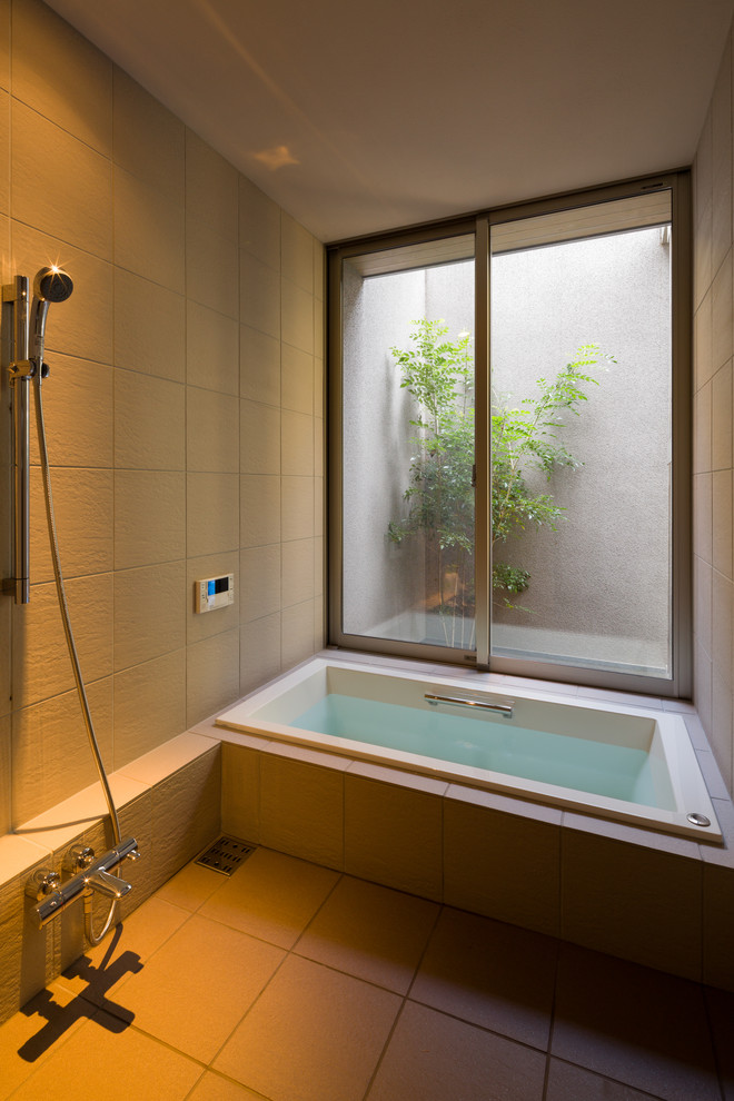 Aménagement d'une salle de bain principale asiatique avec un mur beige, un sol beige, aucune cabine, un carrelage beige, des portes de placard beiges, un bain japonais, un espace douche bain et une fenêtre.