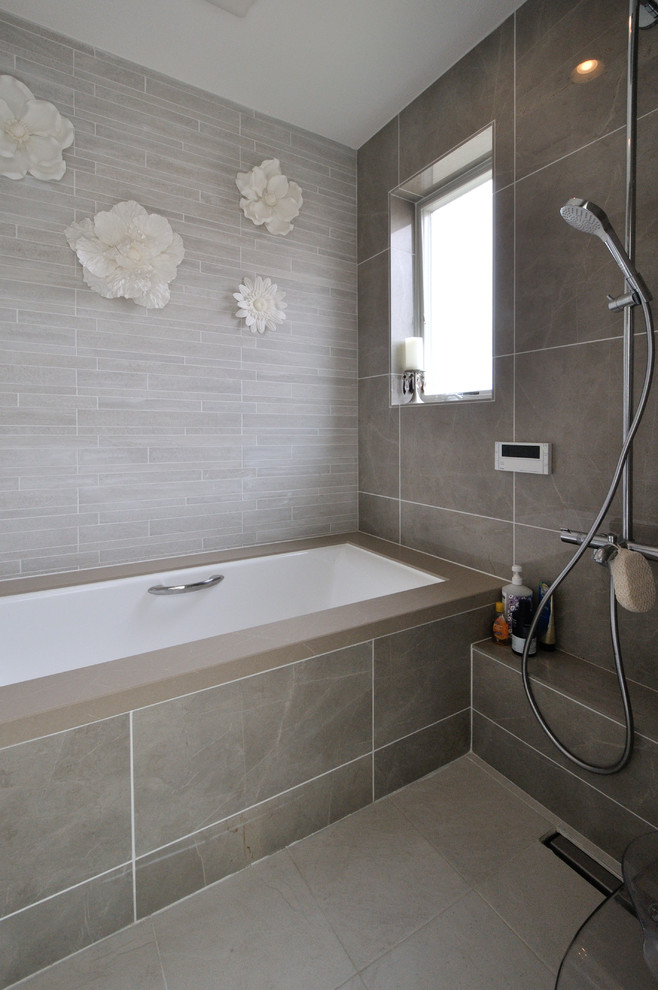 Modern inredning av ett badrum, med ett hörnbadkar, en öppen dusch, grå väggar, grått golv och med dusch som är öppen
