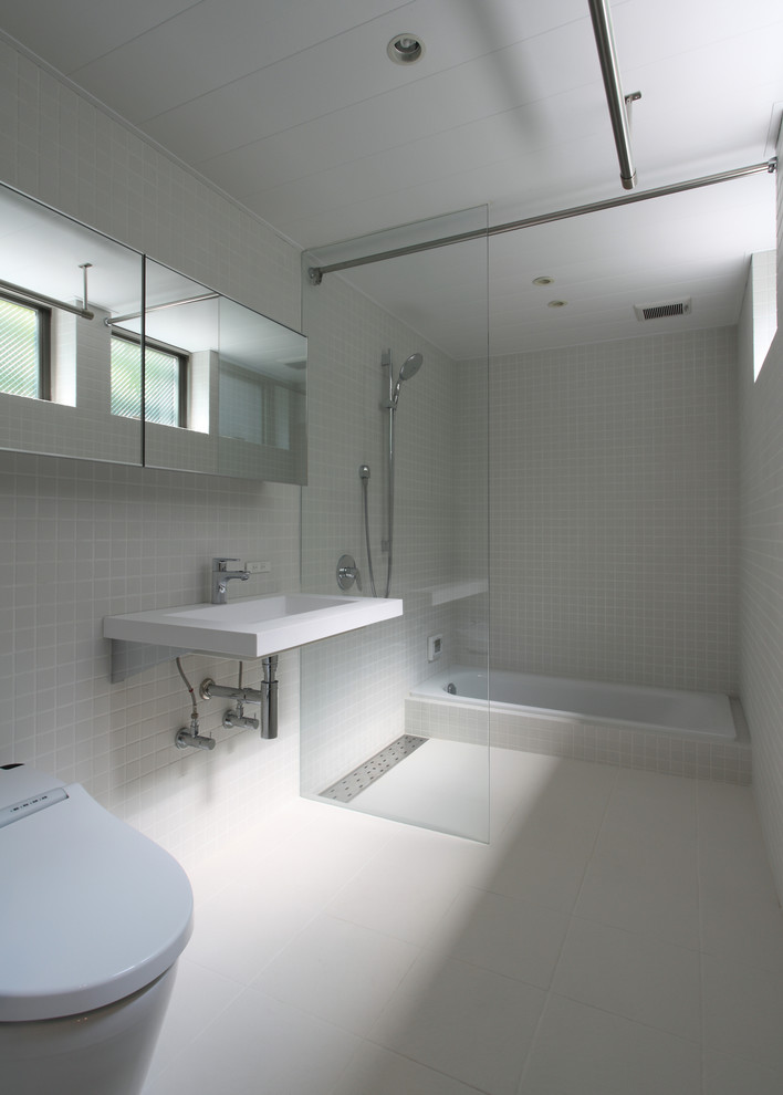 他の地域にあるモダンスタイルのおしゃれな浴室 (ドロップイン型浴槽、オープン型シャワー、壁付け型シンク、白い床、オープンシャワー) の写真