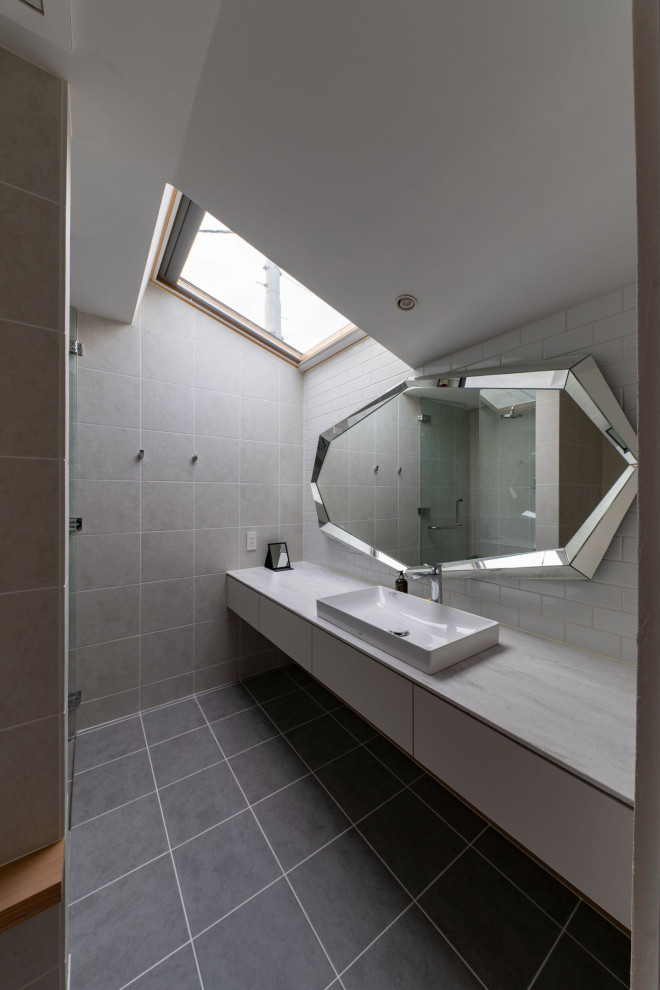Réalisation d'une salle de bain design avec un placard à porte plane, des portes de placard blanches, un carrelage gris, une vasque, un sol gris, un plan de toilette gris, meuble simple vasque, meuble-lavabo suspendu et un plafond voûté.