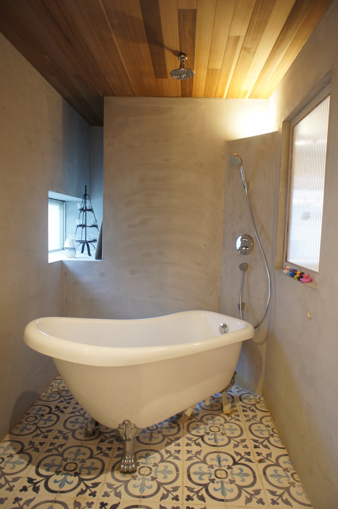 Cette photo montre une petite salle de bain montagne avec une baignoire sur pieds, un combiné douche/baignoire, un mur gris, un sol multicolore et aucune cabine.