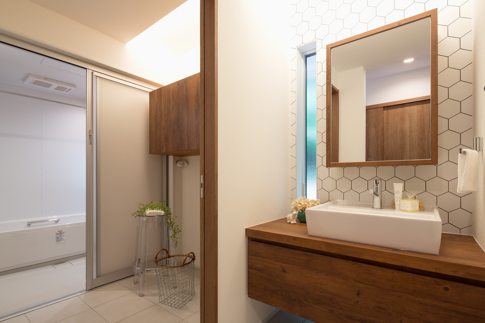 他の地域にあるコンテンポラリースタイルのおしゃれな浴室 (中間色木目調キャビネット、白いタイル、白い壁、ベッセル式洗面器、木製洗面台) の写真