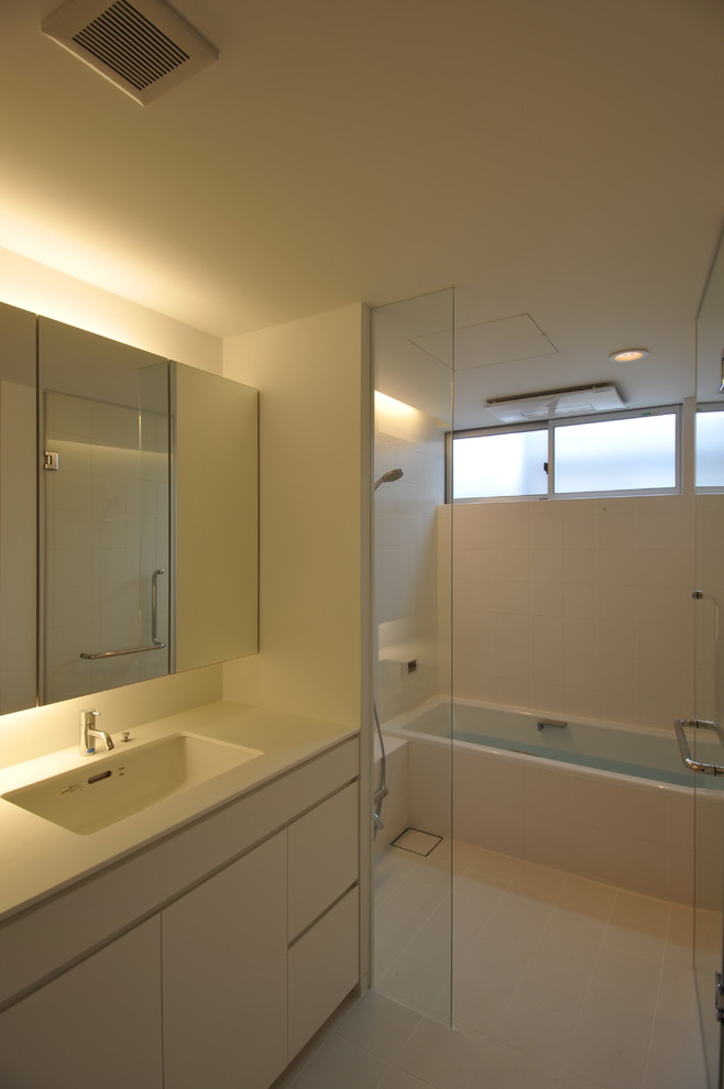 東京23区にある高級な小さなコンテンポラリースタイルのおしゃれなマスターバスルーム (フラットパネル扉のキャビネット、白いキャビネット、ドロップイン型浴槽、オープン型シャワー、白いタイル、セラミックタイル、白い壁、セラミックタイルの床、一体型シンク、人工大理石カウンター、白い床、オープンシャワー、白い洗面カウンター) の写真