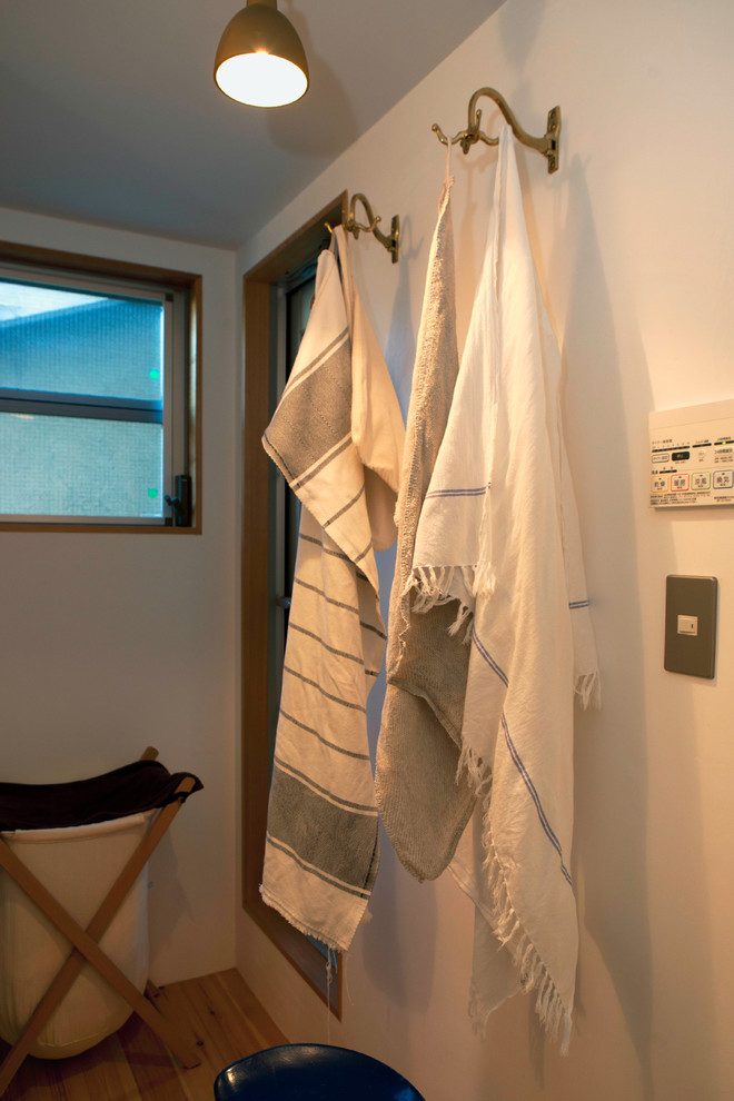 Foto på ett minimalistiskt badrum, med öppna hyllor, vit kakel, keramikplattor, vita väggar, ljust trägolv, ett väggmonterat handfat, bänkskiva i akrylsten och beiget golv