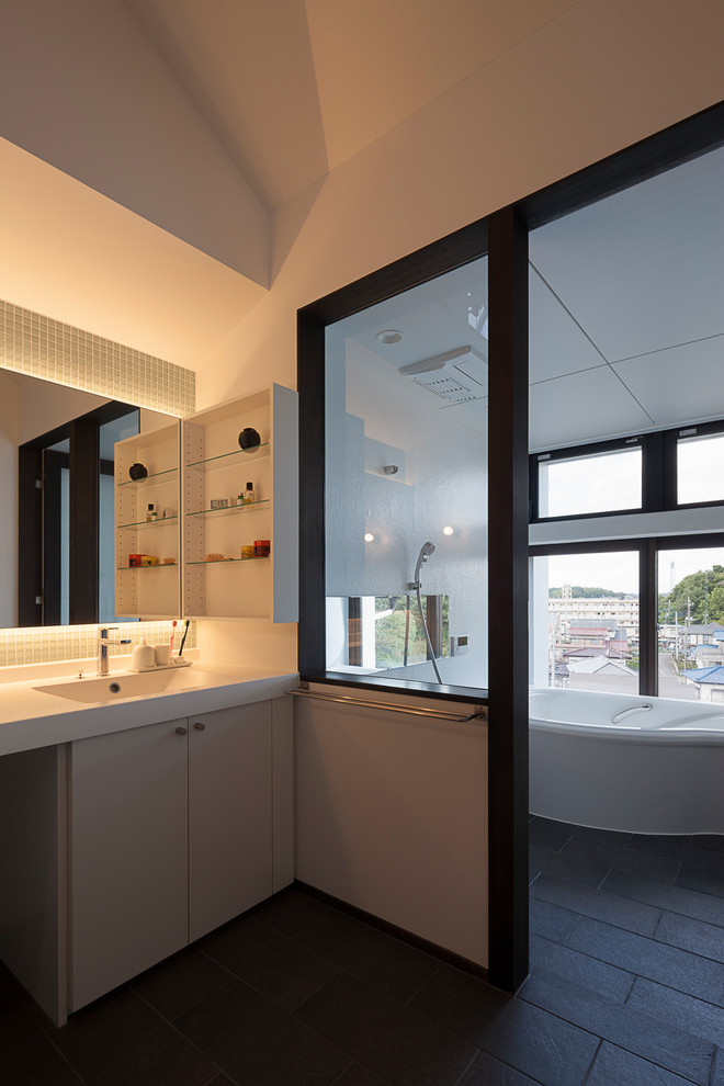 Foto de cuarto de baño contemporáneo con armarios con paneles lisos, puertas de armario beige, paredes blancas, lavabo integrado, suelo negro y encimeras blancas