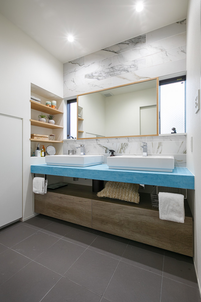 コンテンポラリースタイルのおしゃれな浴室 (中間色木目調キャビネット、グレーの壁、グレーの床、ベッセル式洗面器、フラットパネル扉のキャビネット) の写真