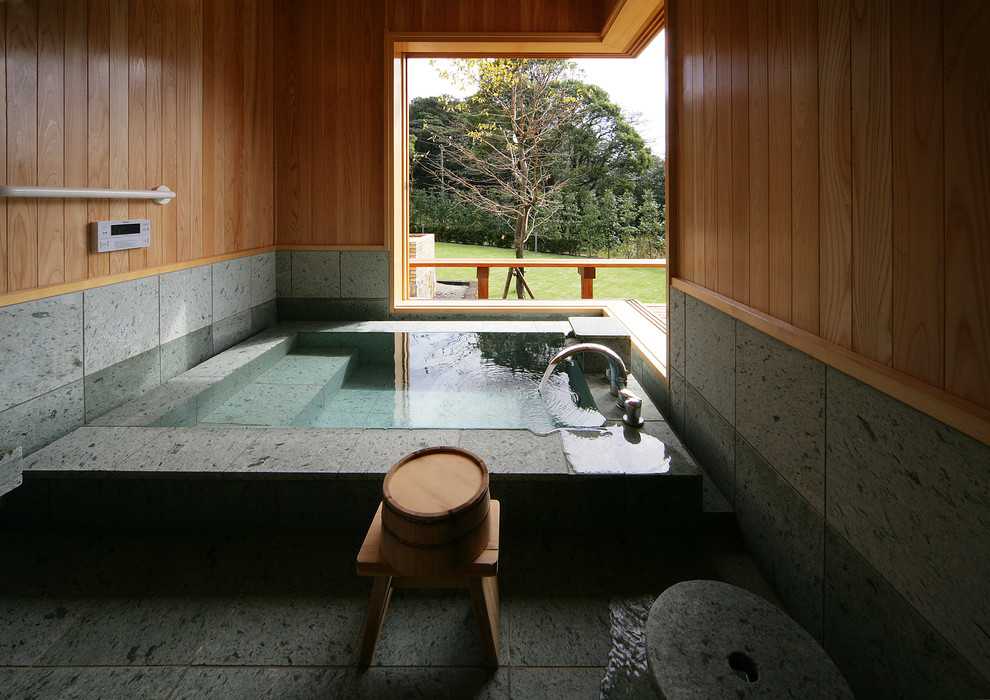 東京都下にあるアジアンスタイルのおしゃれな浴室 (コーナー型浴槽、茶色い壁、グレーの床) の写真