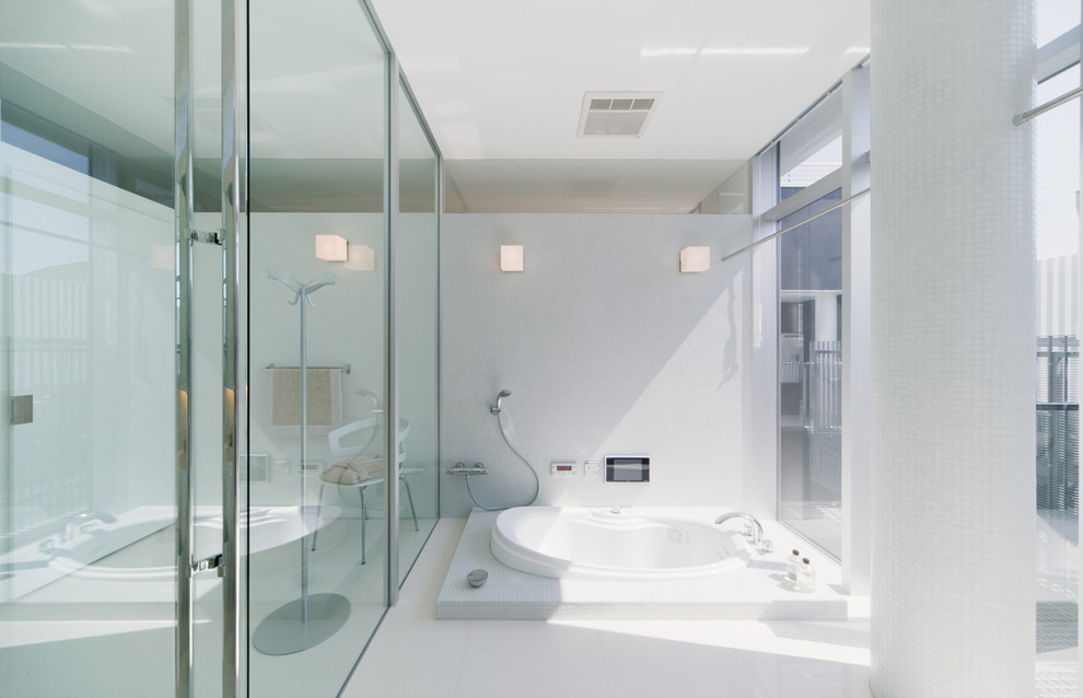 他の地域にあるコンテンポラリースタイルのおしゃれな浴室 (ドロップイン型浴槽、白いタイル、白い壁) の写真