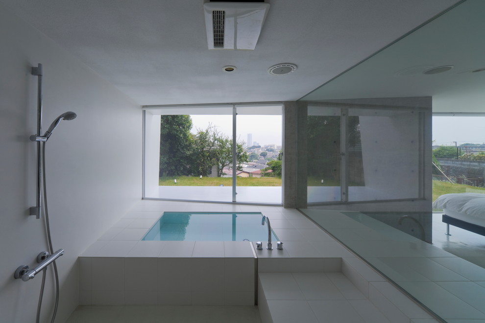 Idée de décoration pour une salle de bain minimaliste avec un bain bouillonnant, un carrelage blanc et un mur blanc.