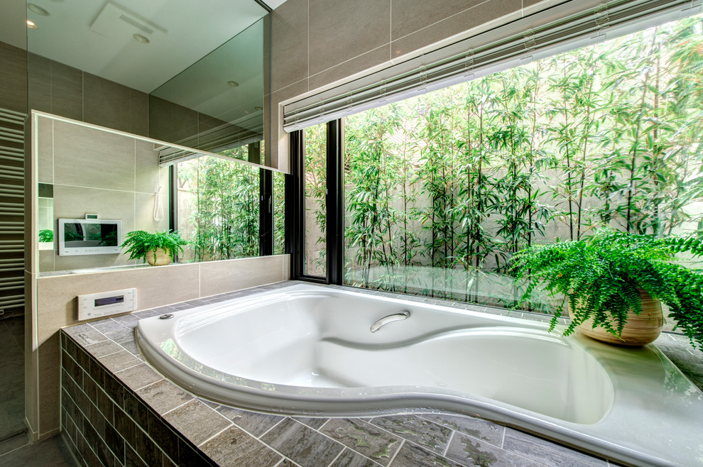 Ejemplo de cuarto de baño principal actual de tamaño medio con bañera encastrada, paredes beige y suelo de pizarra