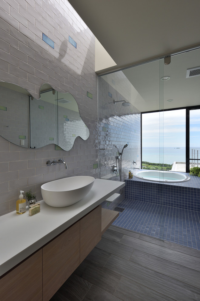 Modernes Badezimmer mit flächenbündigen Schrankfronten, hellen Holzschränken, weißen Fliesen, weißer Wandfarbe, braunem Holzboden, Aufsatzwaschbecken und braunem Boden in Sonstige