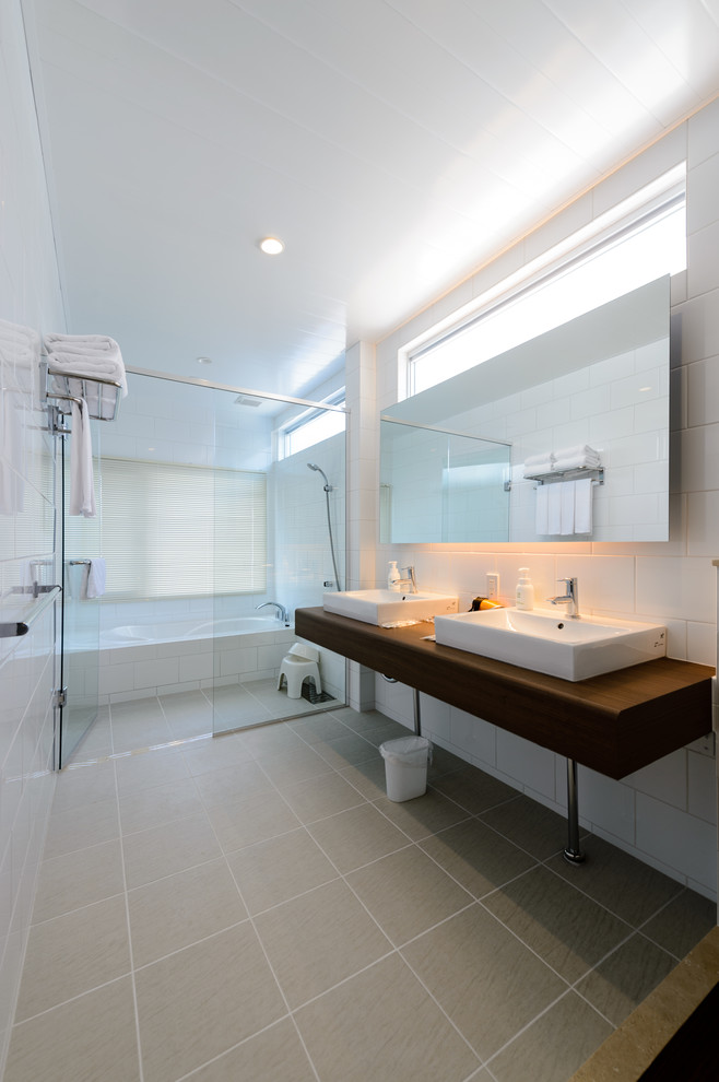 他の地域にあるコンテンポラリースタイルのおしゃれな浴室 (白いタイル、磁器タイル、白い壁、磁器タイルの床、グレーの床、開き戸のシャワー、ブラウンの洗面カウンター) の写真