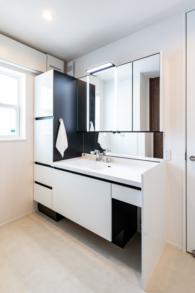Modelo de cuarto de baño actual con armarios con paneles lisos, puertas de armario blancas, paredes blancas, lavabo integrado, suelo beige y encimeras blancas