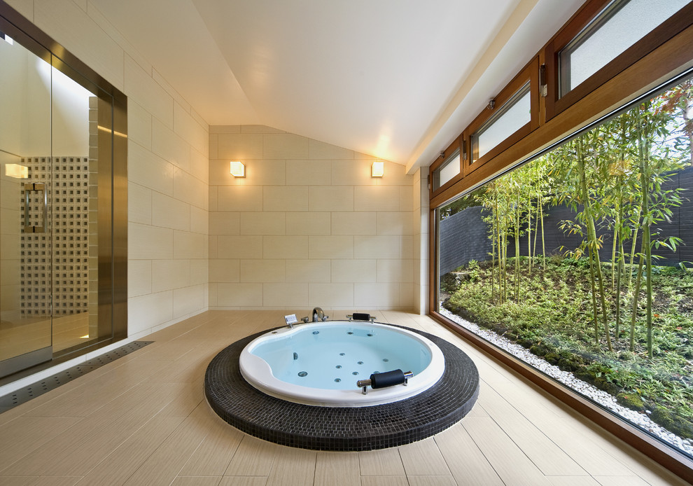 Ejemplo de cuarto de baño asiático con jacuzzi, paredes beige y suelo beige
