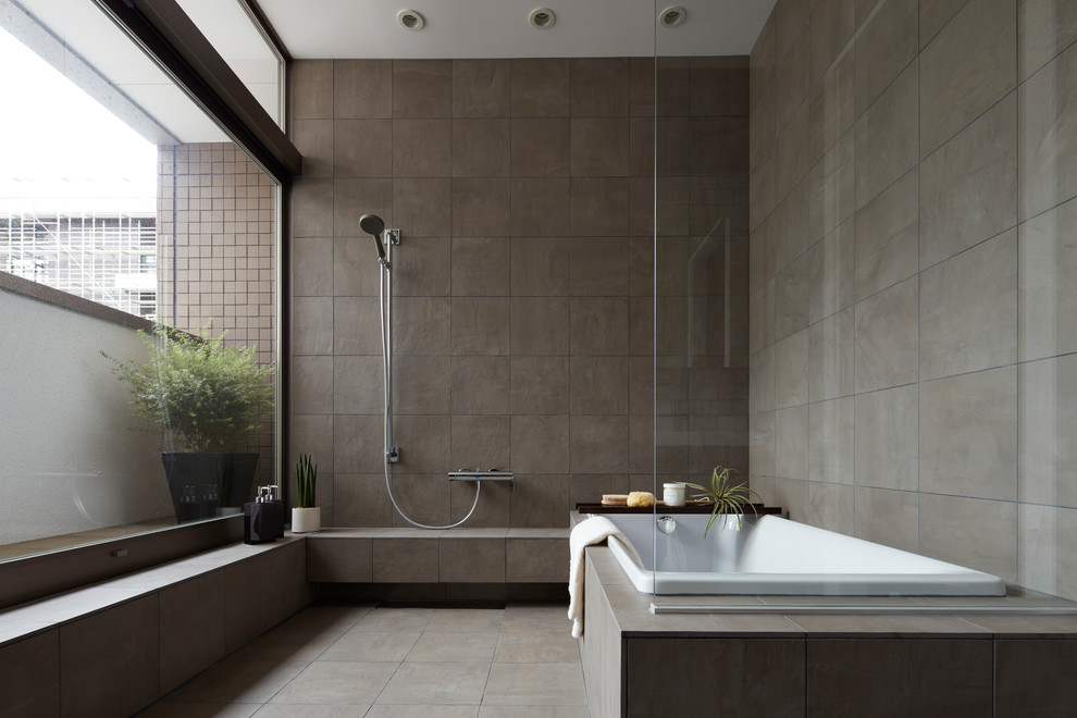 Urban bathroom in Tokyo with a corner bath, a walk-in shower, grey tiles, grey walls, grey floors and an open shower.