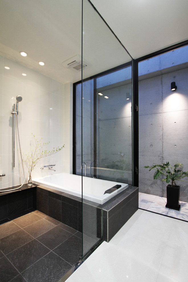 他の地域にあるコンテンポラリースタイルのおしゃれな浴室 (コーナー型浴槽、オープン型シャワー、白い壁、黒い床、オープンシャワー) の写真