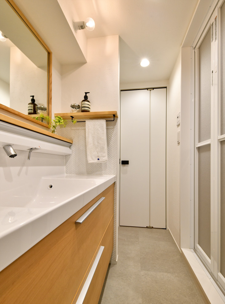 Cette photo montre une grande salle d'eau beige et blanche tendance avec un placard à porte plane, des portes de placard beiges, un mur blanc, un lavabo intégré, un sol gris, un plan de toilette blanc, meuble double vasque et meuble-lavabo encastré.