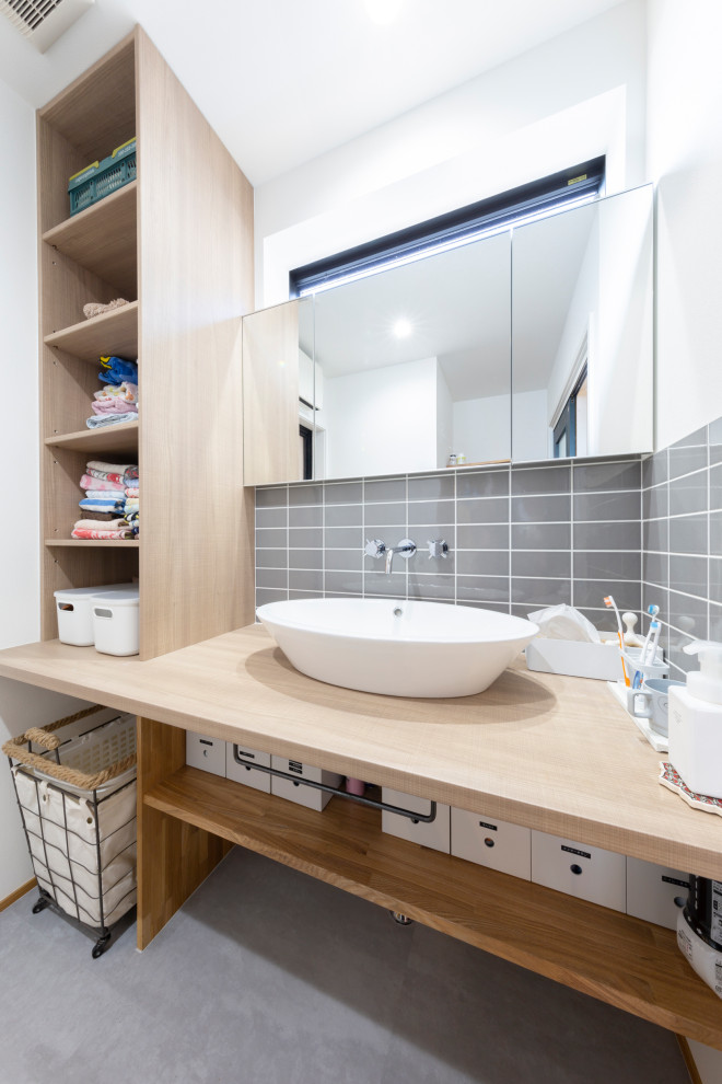 Exemple d'une salle d'eau asiatique en bois clair avec un placard sans porte, un carrelage gris, un carrelage métro, un mur blanc, une vasque, un plan de toilette en bois, un sol gris et un plan de toilette beige.