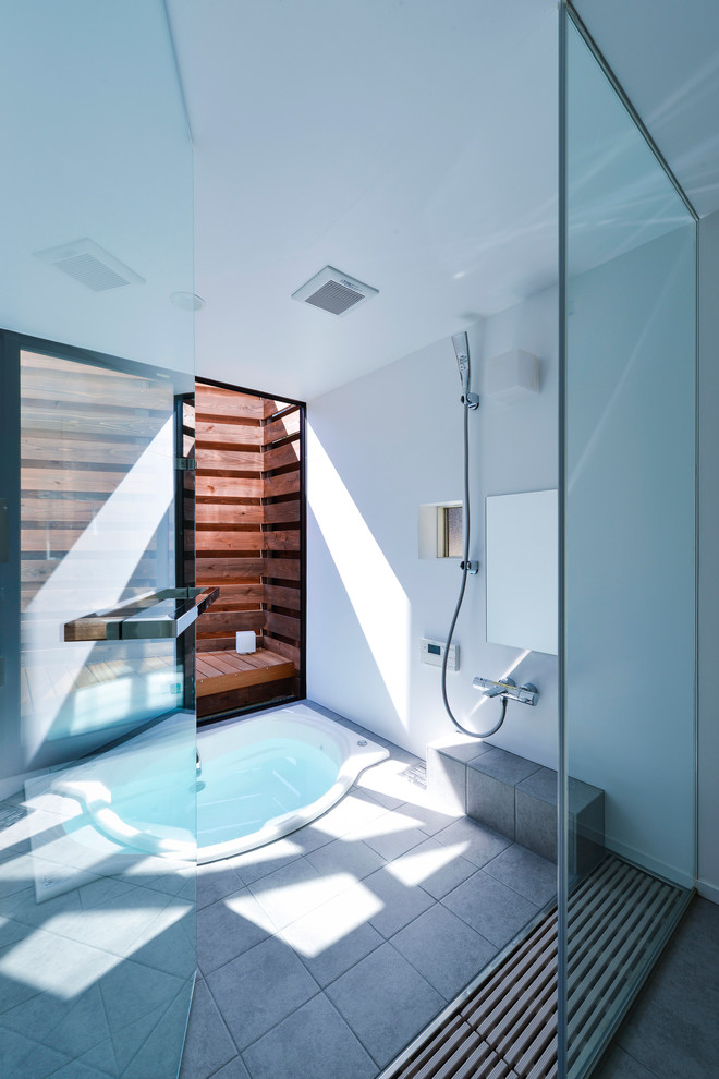 Modernes Badezimmer mit Eckbadewanne, offener Dusche, grauen Fliesen, weißer Wandfarbe, Betonboden und offener Dusche in Sonstige