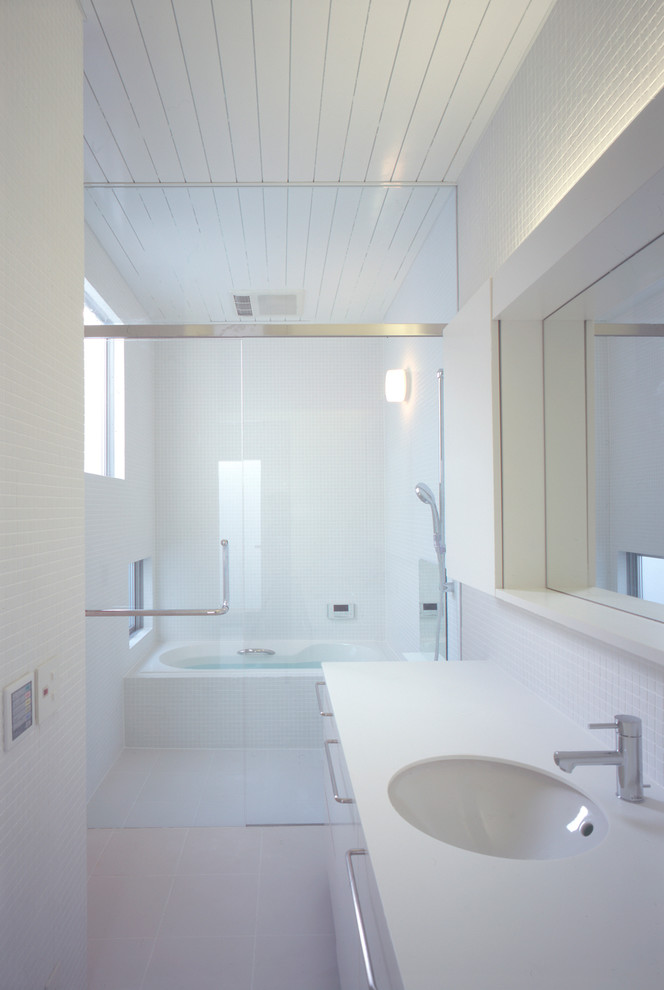 Aménagement d'une salle de bain moderne avec un placard à porte vitrée, des portes de placard blanches, un carrelage blanc et un sol blanc.