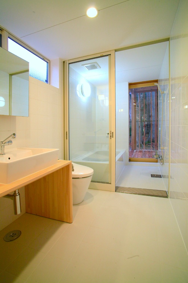 Asiatisches Badezimmer mit braunen Schränken, Eckbadewanne, offener Dusche, weißer Wandfarbe, Aufsatzwaschbecken, Waschtisch aus Holz, weißem Boden und offener Dusche in Sonstige