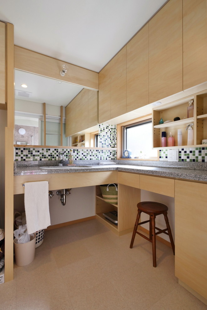 Стильный дизайн: ванная комната в восточном стиле с плоскими фасадами, светлыми деревянными фасадами, зеленой плиткой, белой плиткой, черной плиткой, белыми стенами, монолитной раковиной, столешницей из гранита и коричневым полом - последний тренд