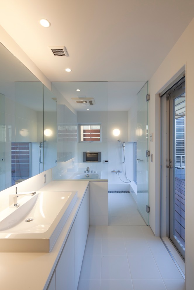 Пример оригинального дизайна: большая главная ванная комната в современном стиле с плоскими фасадами, белыми фасадами, угловой ванной, душевой комнатой, белой плиткой, керамогранитной плиткой, белыми стенами, полом из керамогранита, настольной раковиной, столешницей из искусственного камня, белым полом, открытым душем, белой столешницей и зеркалом с подсветкой