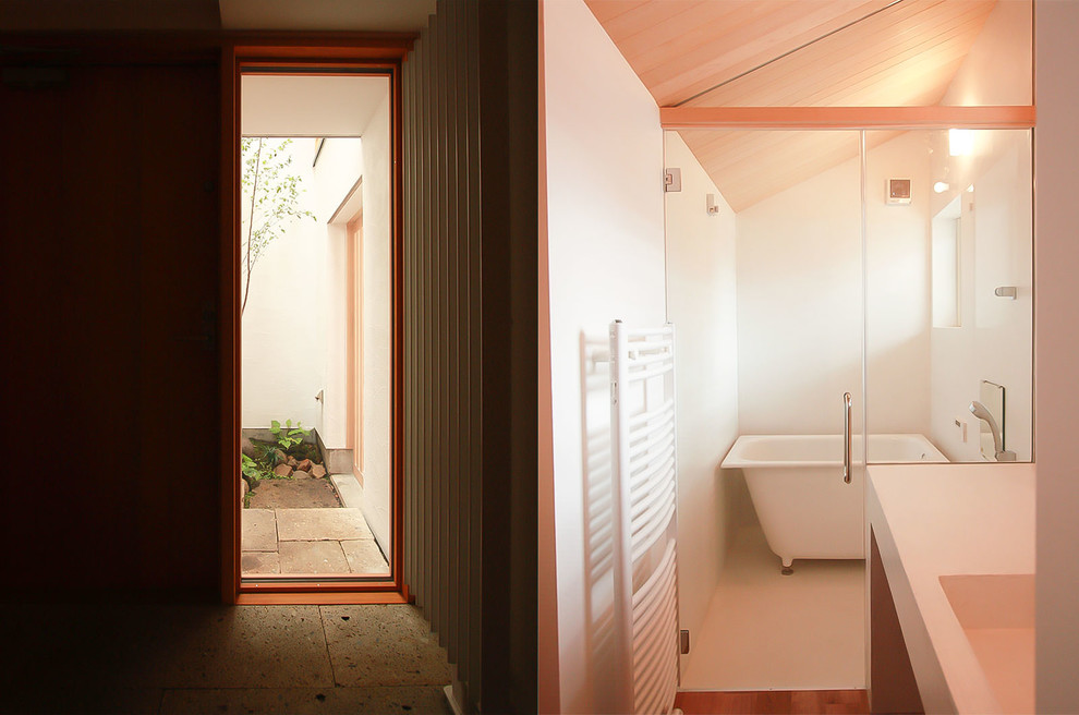 Modelo de cuarto de baño minimalista con bañera exenta, baldosas y/o azulejos blancos, lavabo integrado y encimera de cemento