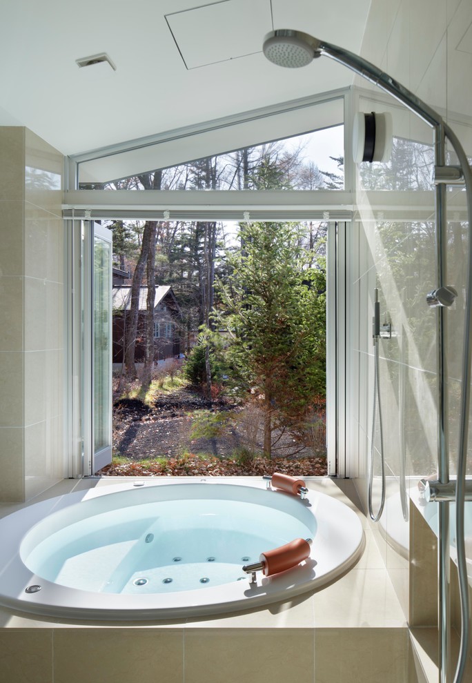 Cette image montre une salle de bain design avec une baignoire posée, un carrelage beige, un mur beige, une douche à l'italienne et des carreaux de céramique.