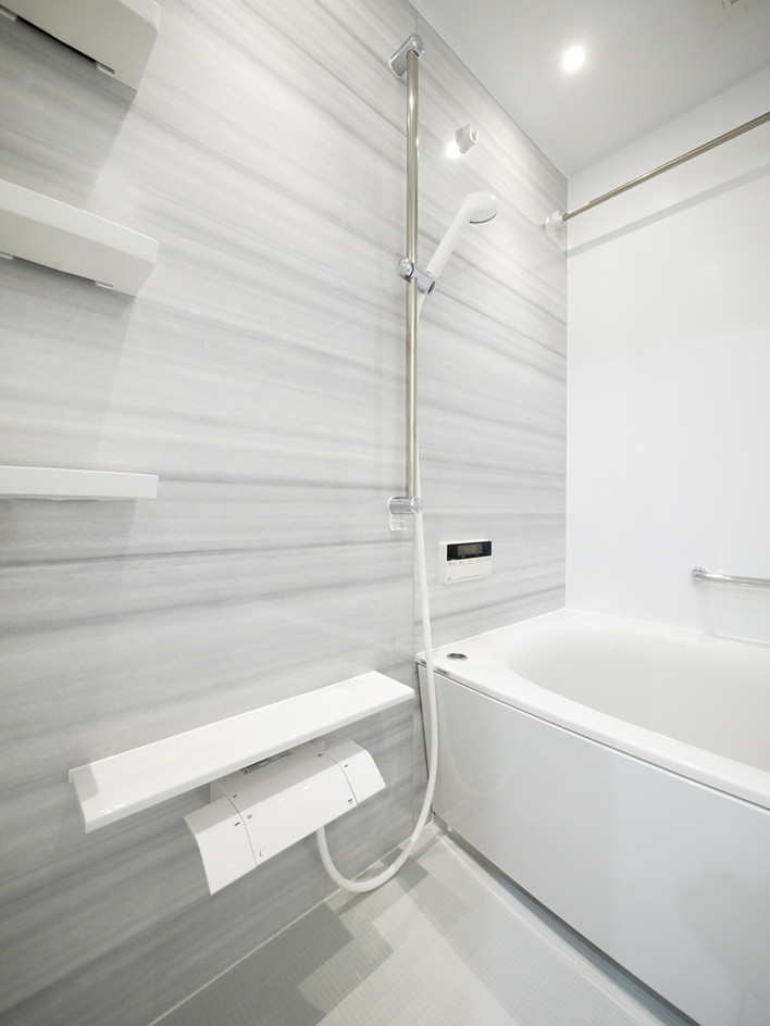 Réalisation d'une salle de bain principale nordique avec un bain japonais, un espace douche bain, un mur gris, une cabine de douche à porte battante, un plan de toilette blanc et du lambris.