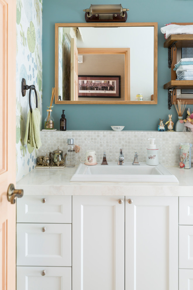 На фото: ванная комната в стиле шебби-шик с фасадами с утопленной филенкой, белыми фасадами, белой плиткой, плиткой мозаикой, синими стенами, накладной раковиной, белой столешницей, тумбой под одну раковину и обоями на стенах
