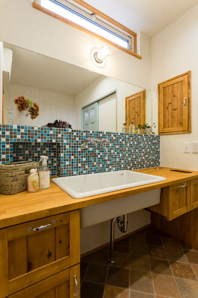 Imagen de cuarto de baño marinero con armarios con paneles empotrados, puertas de armario marrones, baldosas y/o azulejos marrones, baldosas y/o azulejos multicolor, baldosas y/o azulejos blancos, baldosas y/o azulejos azules, paredes beige, lavabo encastrado, encimera de madera, suelo marrón y encimeras marrones