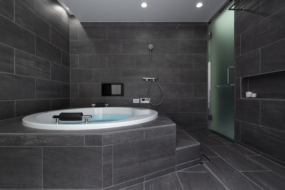 Exemple d'une salle de bain moderne avec un bain bouillonnant, des carreaux de porcelaine, un mur gris, un sol en carrelage de porcelaine et un sol gris.