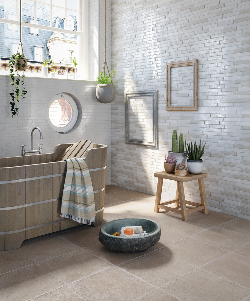 Cette image montre une salle de bain bohème avec une baignoire indépendante, un mur beige et un sol beige.
