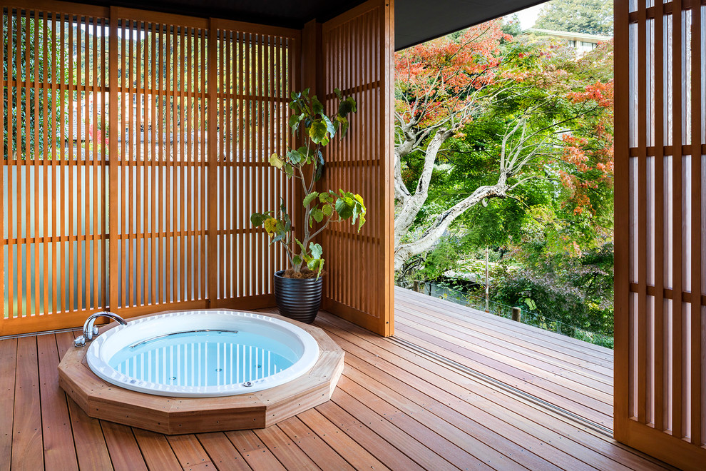 Asiatisches Badezimmer mit japanischer Badewanne, dunklem Holzboden und braunem Boden in Sonstige