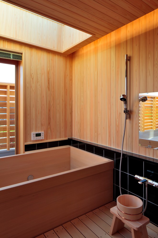 Ispirazione per una stanza da bagno padronale etnica con vasca giapponese, piastrelle nere, pareti beige, soffitto in legno e pareti in legno