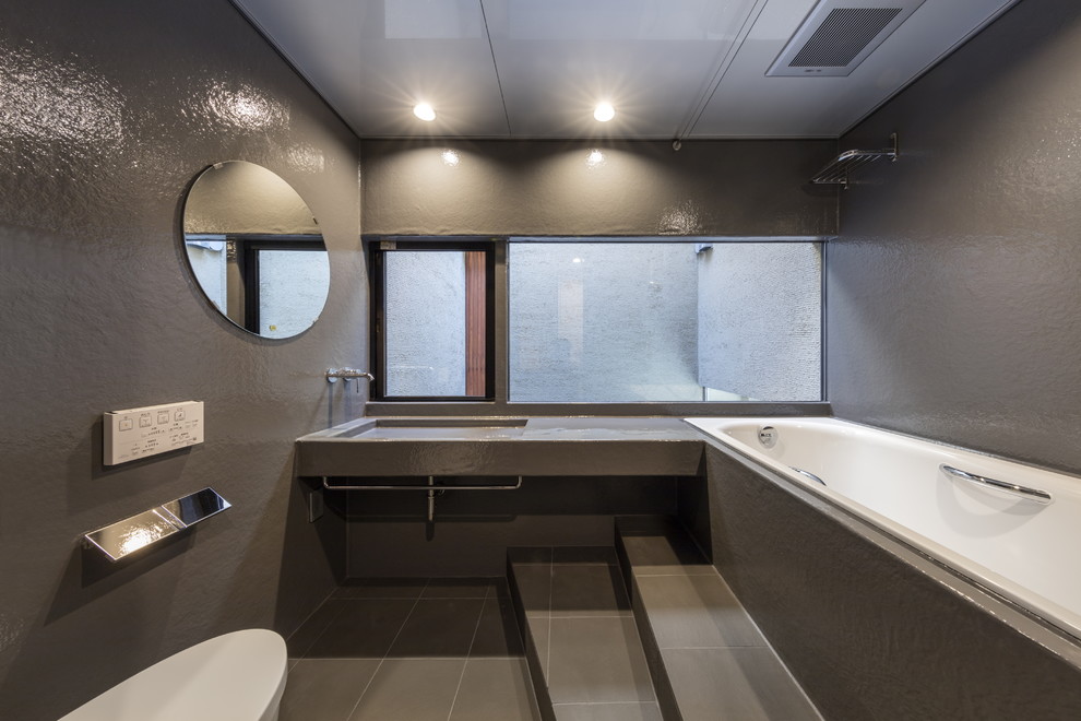 Diseño de cuarto de baño contemporáneo con bañera encastrada, paredes grises y suelo gris