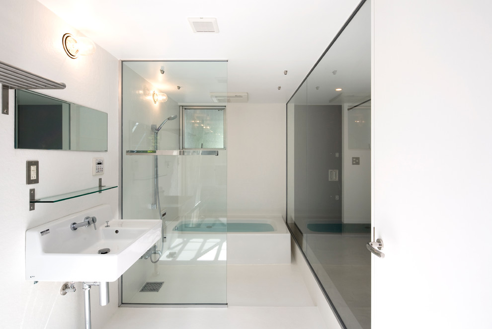 Стильный дизайн: ванная комната в стиле модернизм с угловой ванной, открытым душем, белыми стенами, подвесной раковиной, белым полом и открытым душем - последний тренд