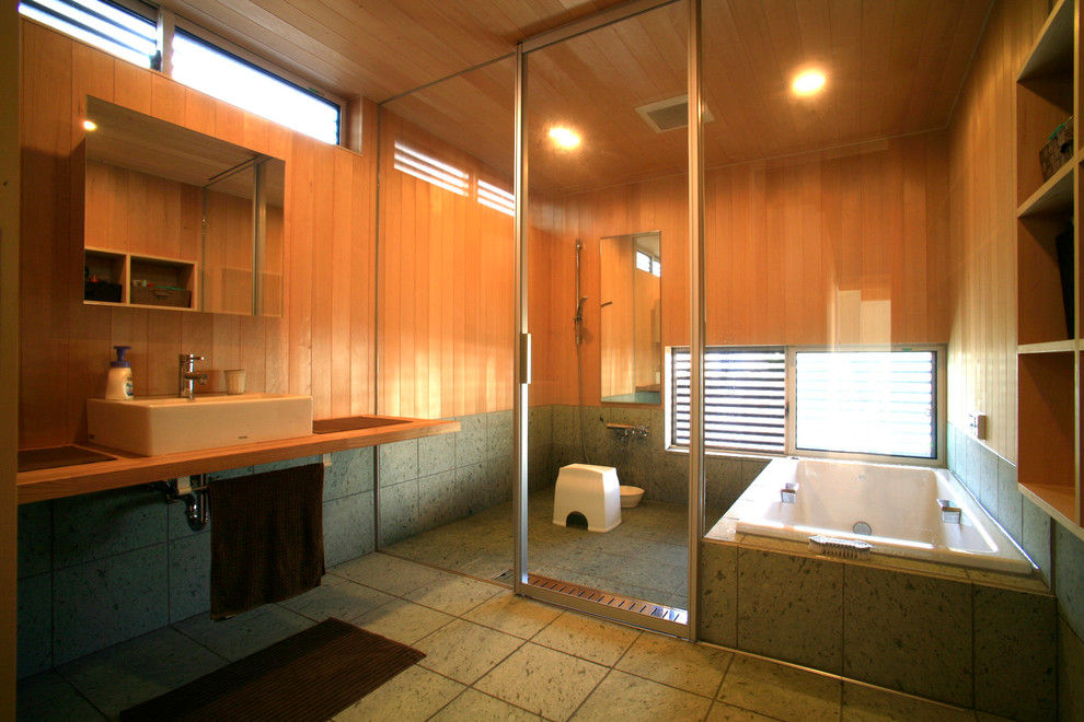 他の地域にある和風のおしゃれな浴室 (中間色木目調キャビネット、コーナー型浴槽、オープン型シャワー、マルチカラーの壁、ベッセル式洗面器、木製洗面台、グレーの床、オープンシャワー) の写真