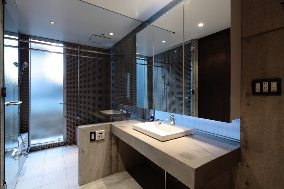 Foto di una stanza da bagno industriale con vasca ad angolo, doccia aperta, piastrelle nere, pareti grigie, lavabo da incasso, top in cemento e pavimento grigio