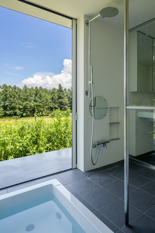 Immagine di una stanza da bagno moderna con vasca freestanding, doccia a filo pavimento e doccia aperta