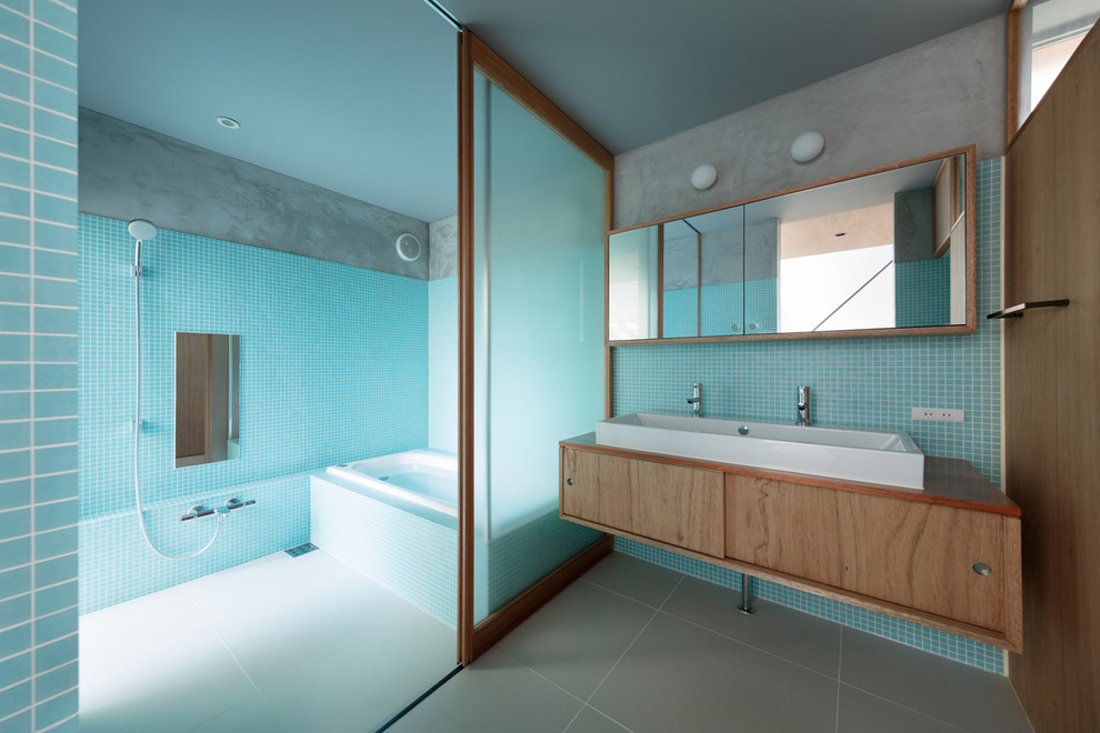 Идея дизайна: ванная комната в стиле лофт с плоскими фасадами, фасадами цвета дерева среднего тона, угловой ванной, открытым душем, синей плиткой, синими стенами, настольной раковиной, столешницей из дерева, серым полом и открытым душем