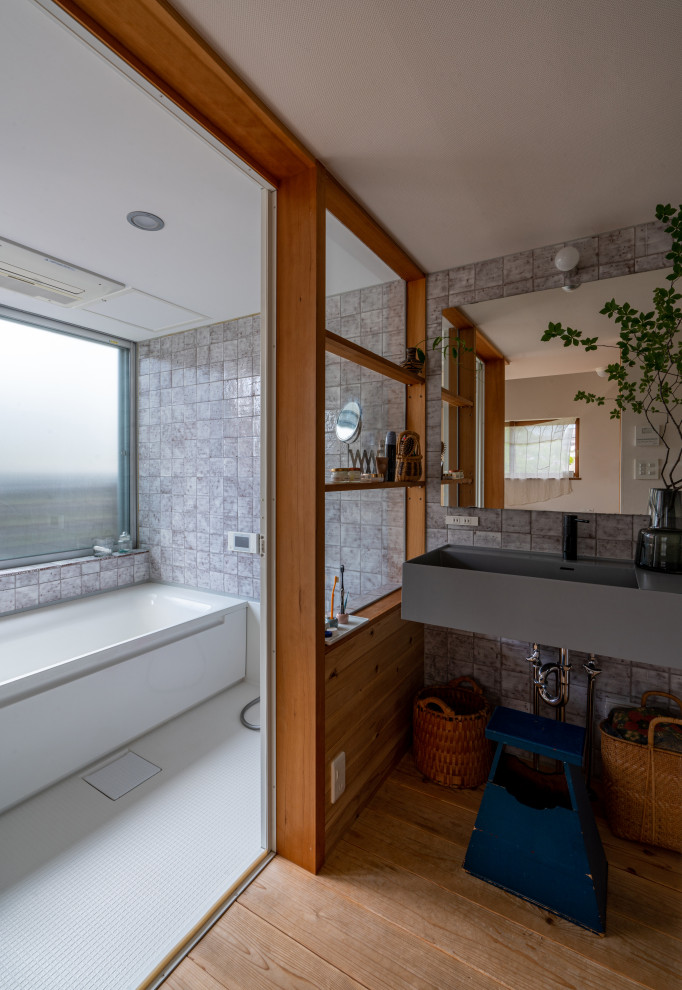 Idéer för att renovera ett orientaliskt badrum, med ett badkar i en alkov, våtrum, grå kakel, mellanmörkt trägolv, ett väggmonterat handfat och brunt golv