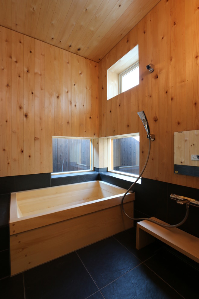 Ejemplo de cuarto de baño asiático con bañera exenta, ducha abierta, paredes marrones, suelo negro y ducha abierta