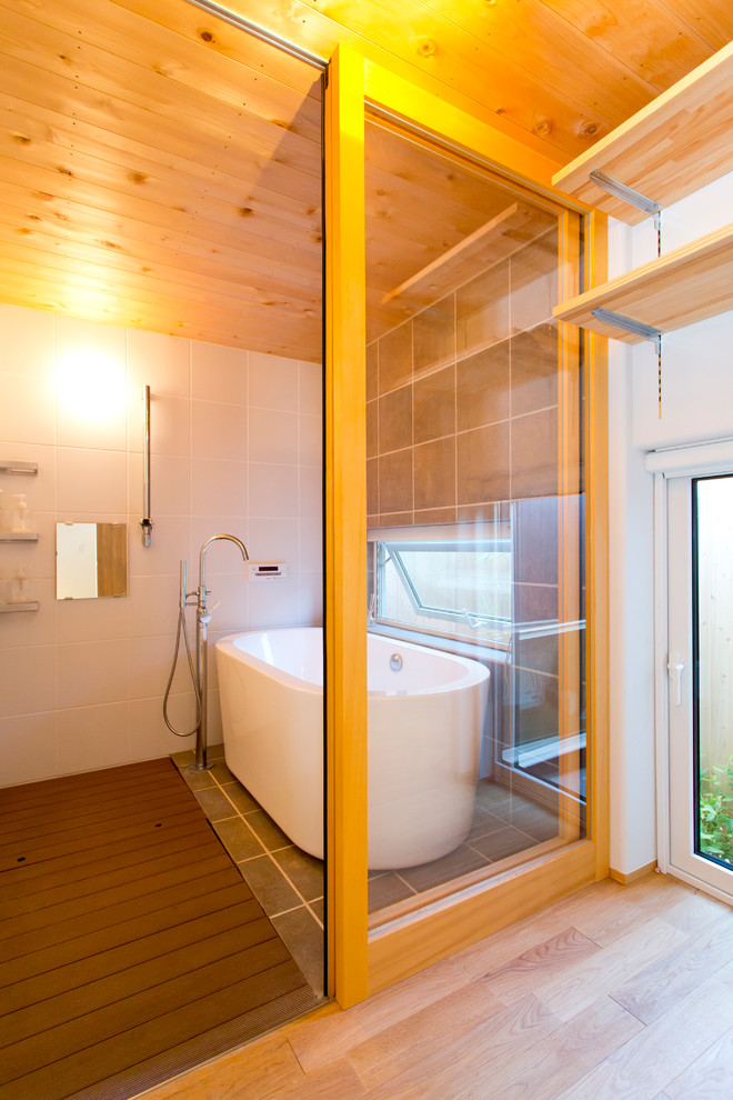 Foto di una stanza da bagno design con vasca freestanding, doccia aperta, piastrelle bianche, pareti grigie, pavimento grigio e doccia aperta